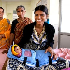 A happy mother holding her newborn in an embrace warmer 